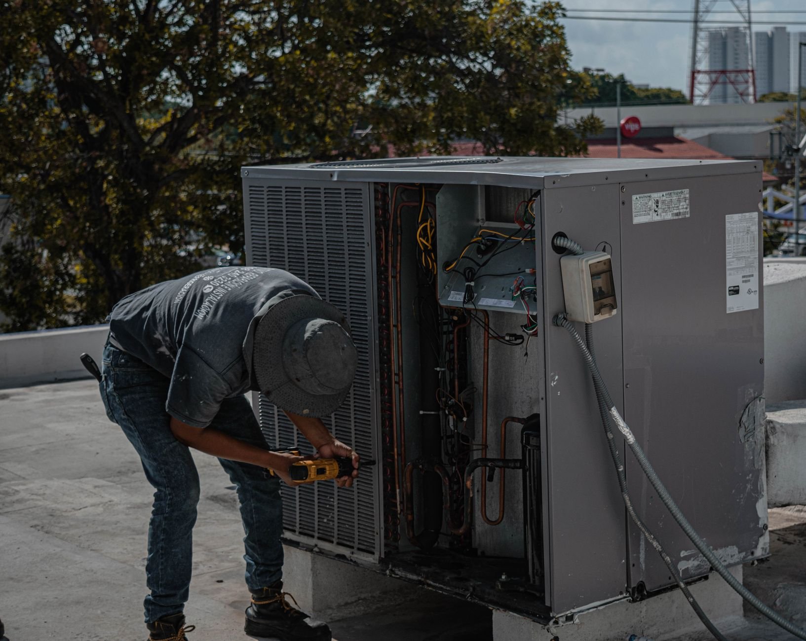 A technician servicing an air conditioning unit on a rooftop